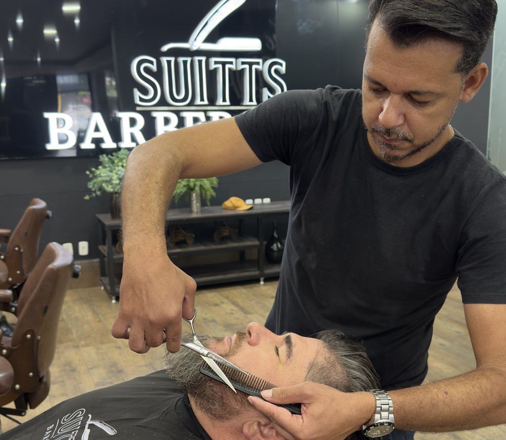 Barbeiro aparando barba com tesoura e pente